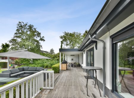 Terrace at the back of the house with a small sitting area under a canopy on a wooden floor and a dining area under the roof